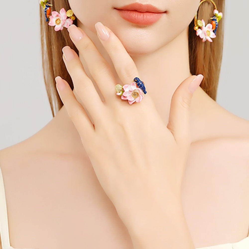 Angled image of a gold ring with pink lotus flower and blue kingfisher bird on a white background