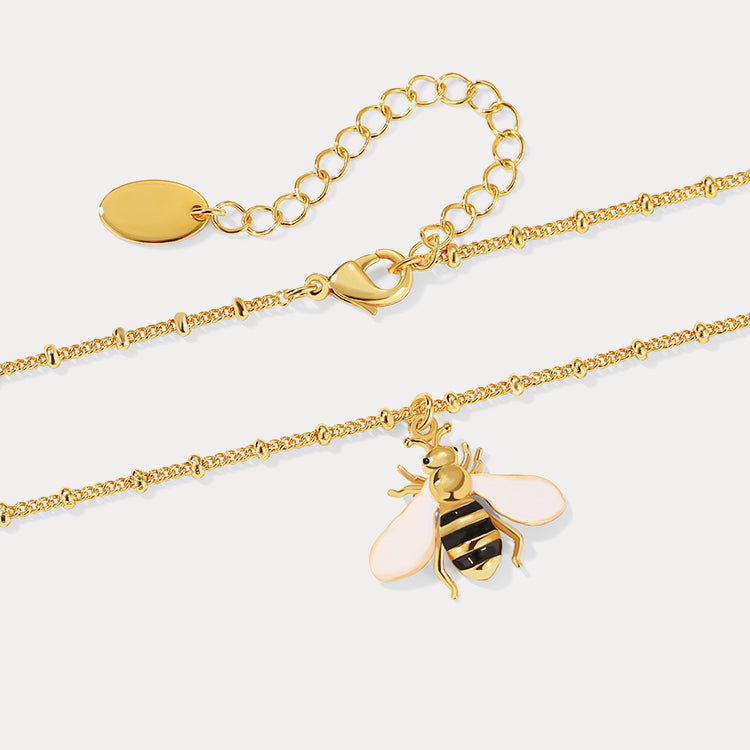 Close-up of gold bee charm with adjustable chain and lobster clasp, highlighting pink wings and gold finish