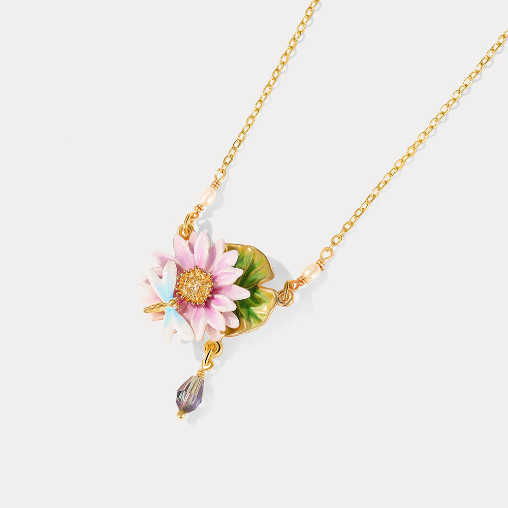 Close-up of lotus dragonfly necklace showcasing pink enamel lotus, green leaf, blue dragonfly, and crystal drop charm.