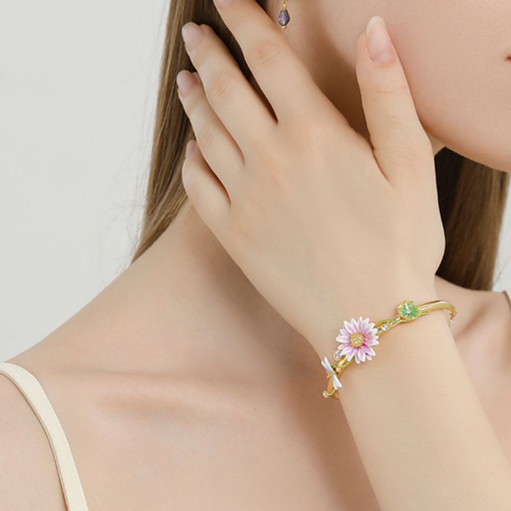 Top view of Lotus Dragonfly Bracelet showcasing a pink lotus blossom, dragonfly charm, and gold-tone band