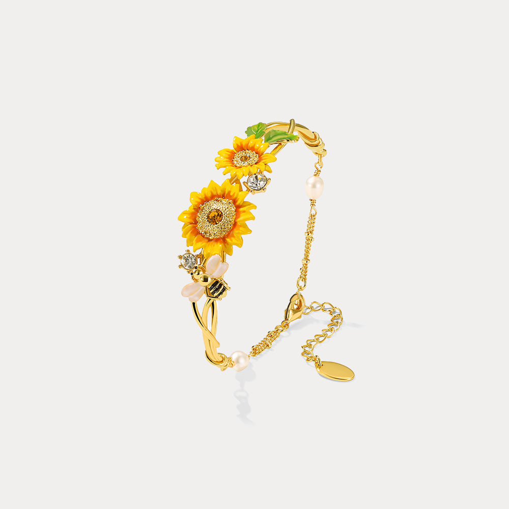 Flat lay of sunflower cuff bracelet with adjustable chain, sunflower charms, bee, and pearl details
