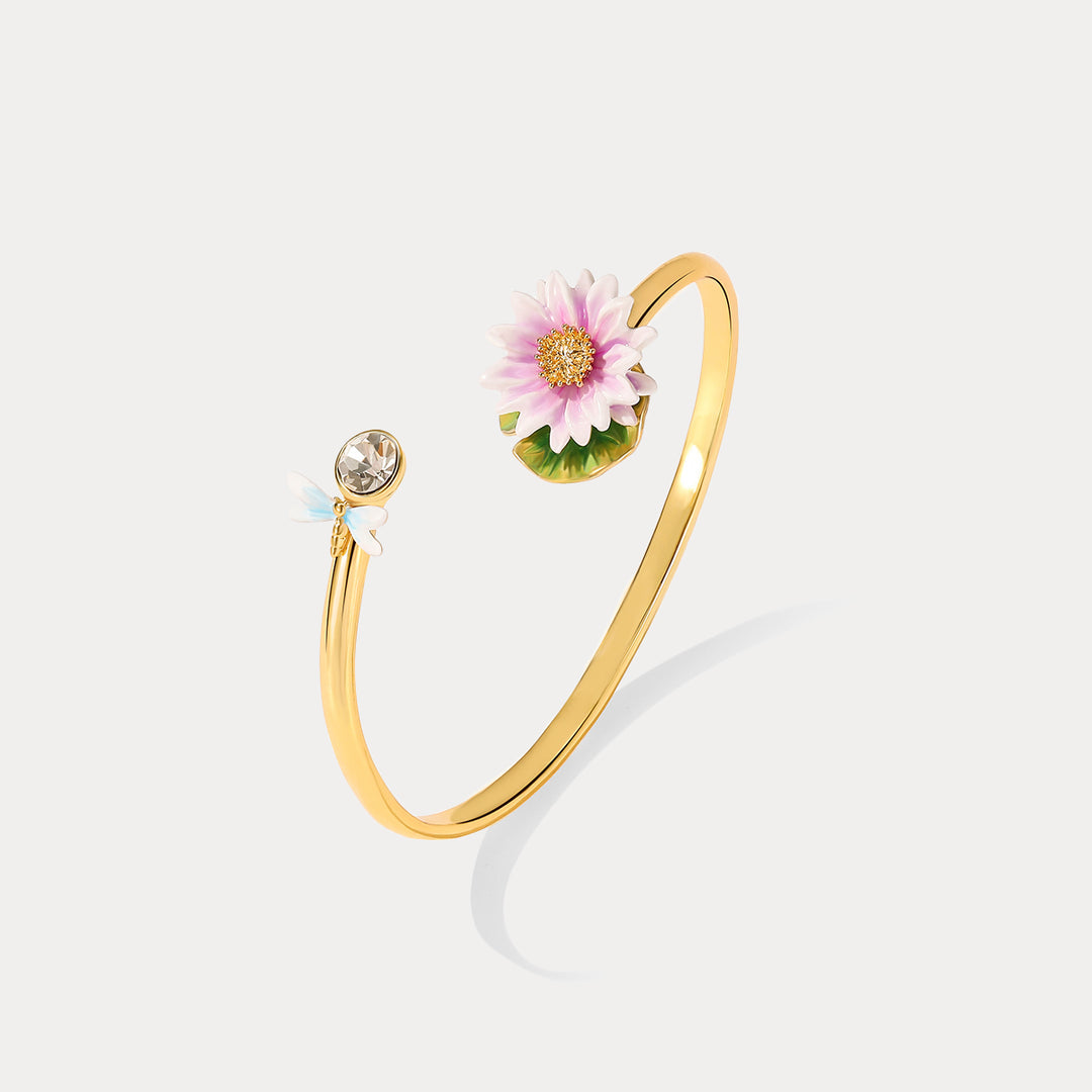 Top flat lay image of the Lotus Dragonfly Bracelet featuring a delicate pink lotus and blue dragonfly motif with a gold band.
