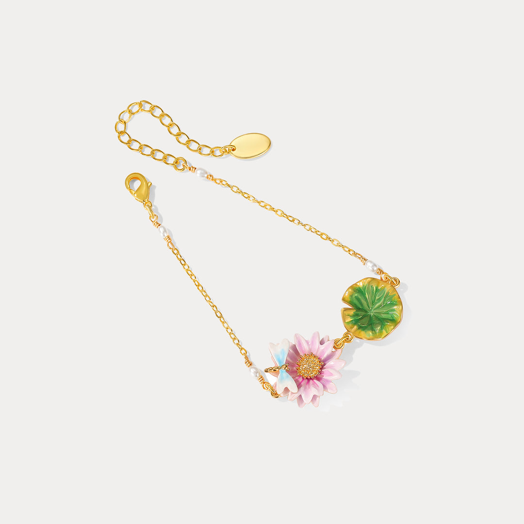 Close-up top view of lotus dragonfly bracelet with pink enamel lotus flower, gold chain, and green leaf detail.