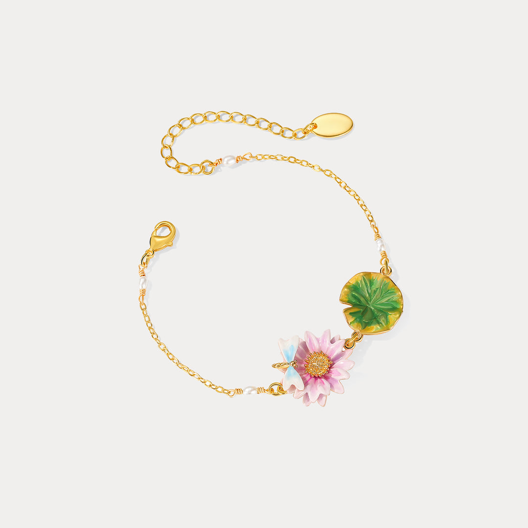 Gold bracelet featuring enamel pink lotus flower and green lotus leaf charm, accented with pearls and a dragonfly.