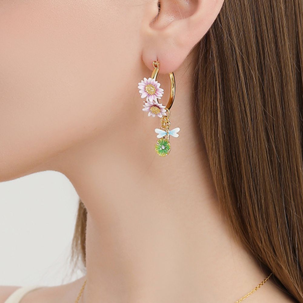 Close-up of the hoop earrings worn on a model's ear, highlighting the enamel lotus flowers and hanging dragonfly charm.