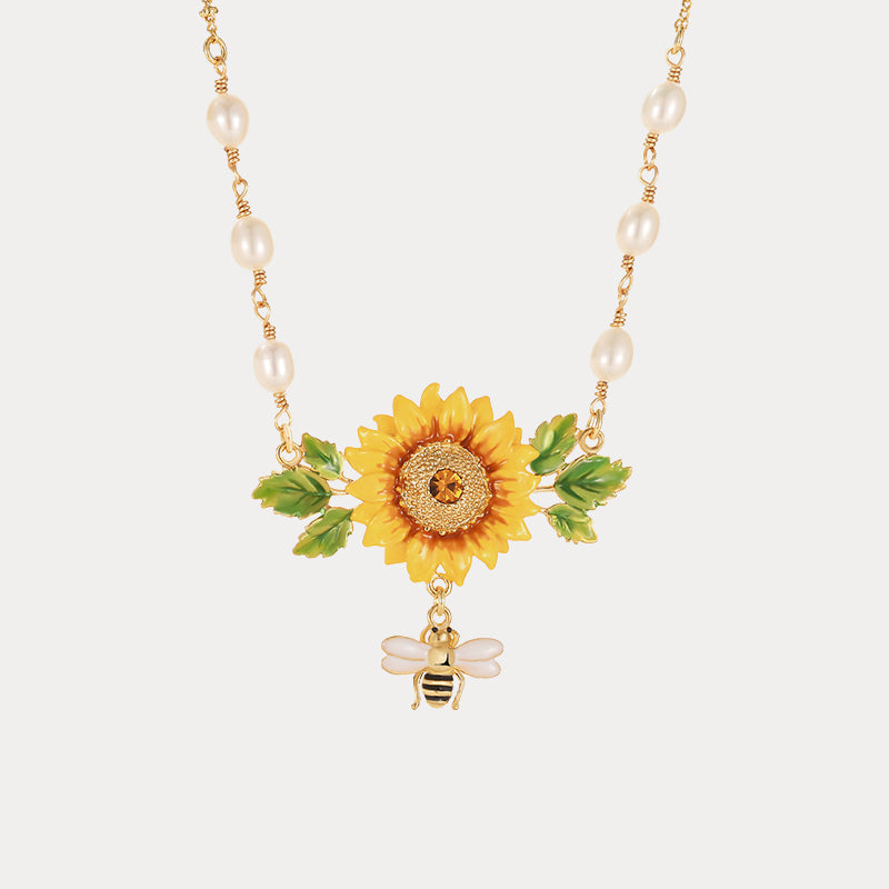 Detailed shot of sunflower enamel pendant with gold accents, pearls, and dangling bee charm