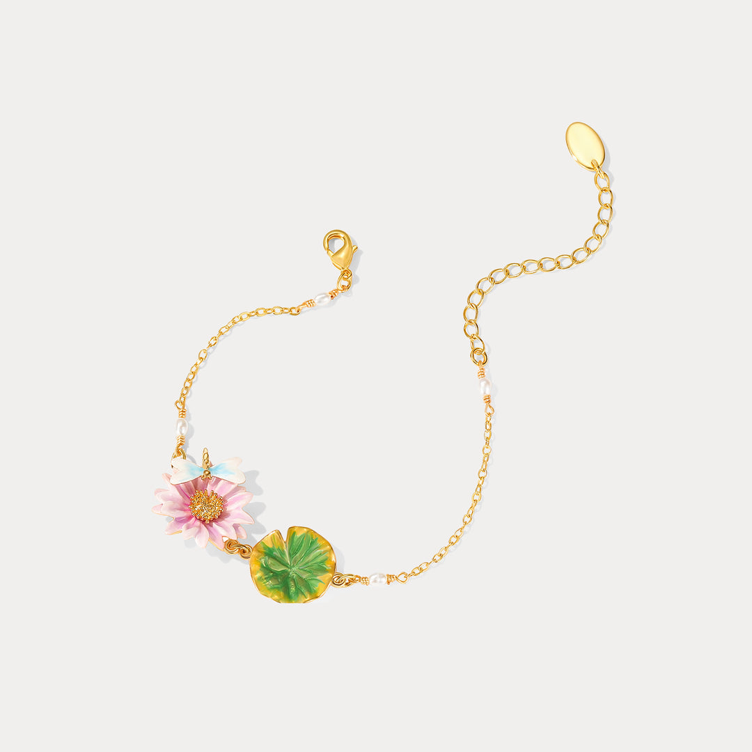 Side angle of lotus dragonfly bracelet showing pink lotus enamel flower, green leaf charm, and gold-tone chain.