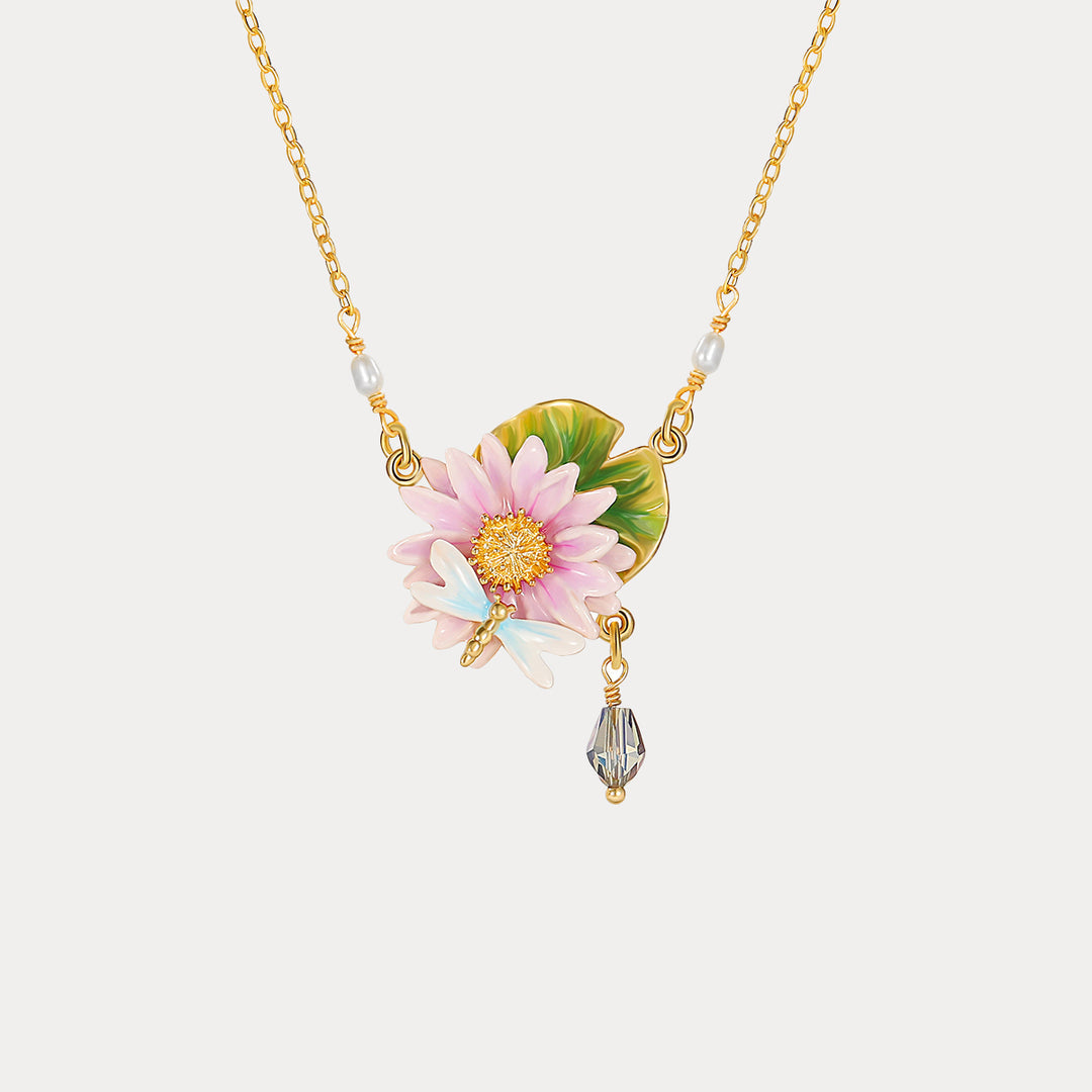 Studio image of lotus dragonfly necklace centered on white background, showcasing enamel flower and dragonfly with pearl details.