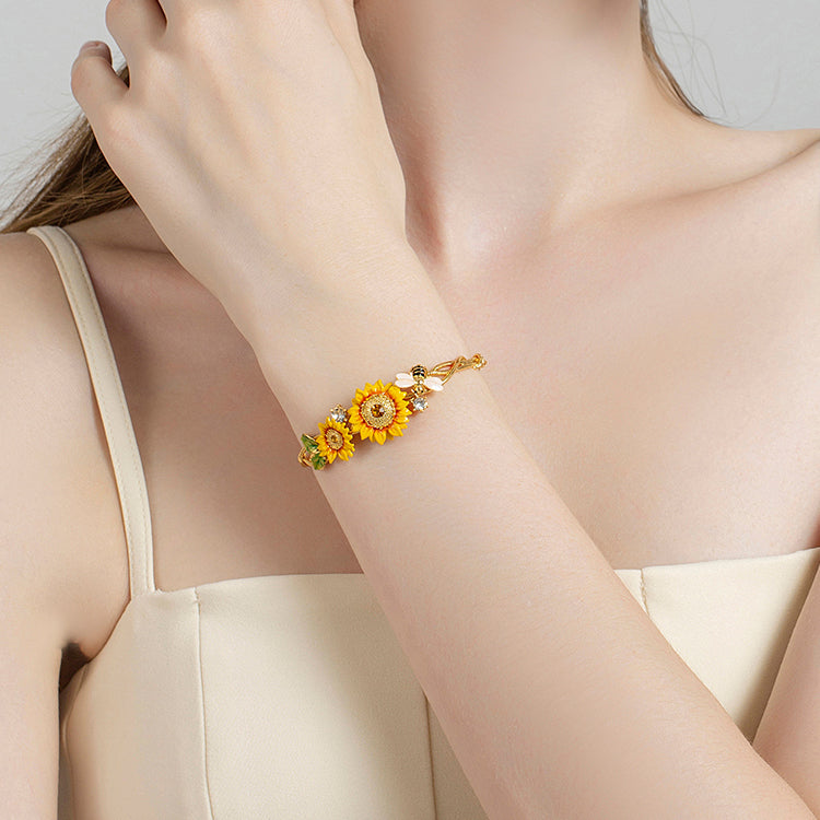 Close-up of woman showcasing sunflower bracelet on her arm, highlighting the floral and bee details