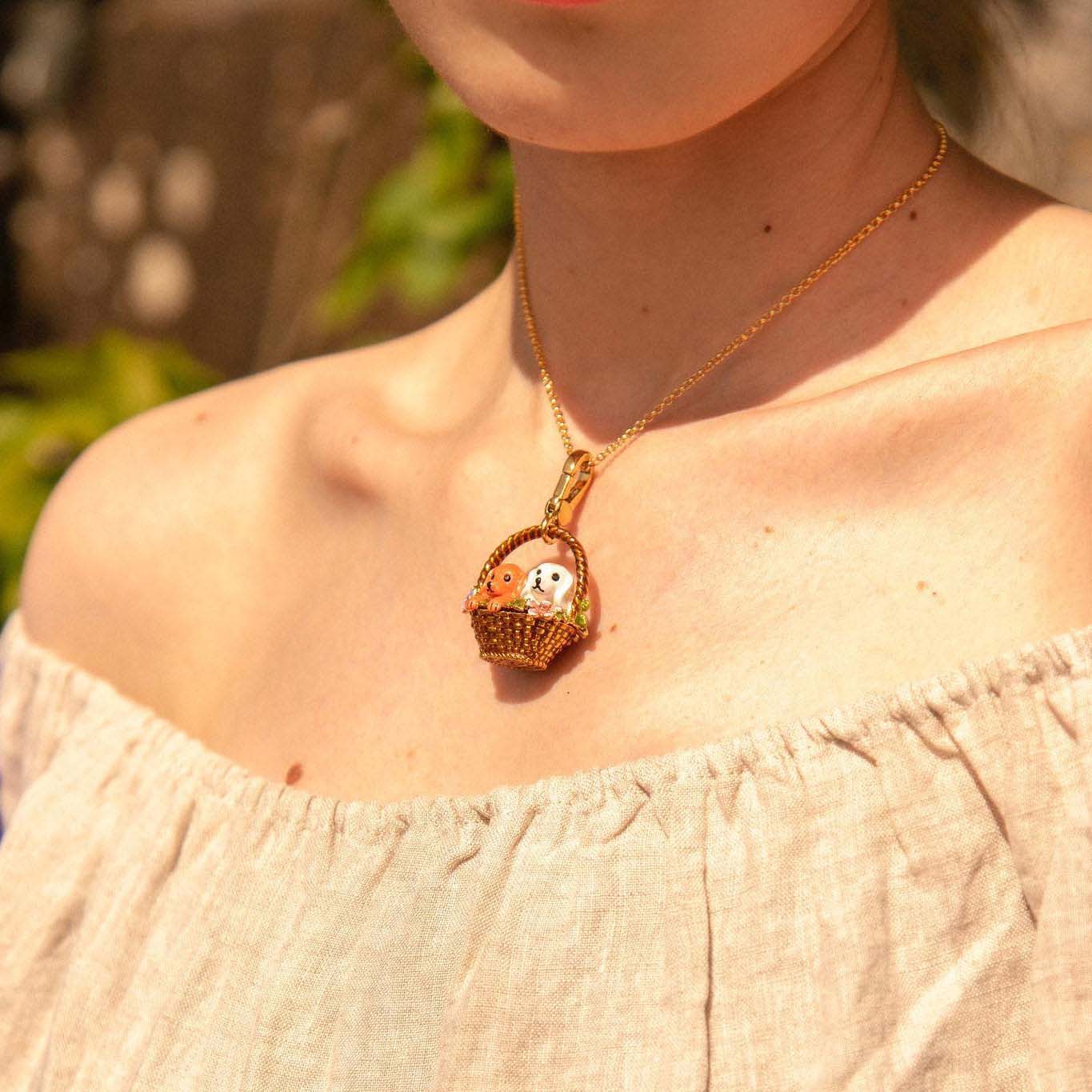 Close-up of a woman wearing the Puppy Locket Pendant Necklace by Verdivine, featuring two enamel dogs in a floral basket.