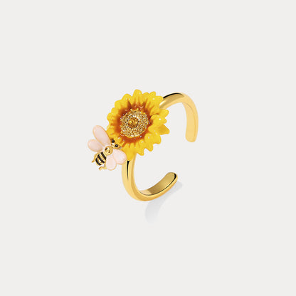 Gold-tone adjustable ring with sunflower enamel and bee charm shown on white background