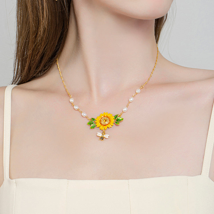 Zoomed-in chest view showing sunflower enamel pendant with bee charm and pearl links