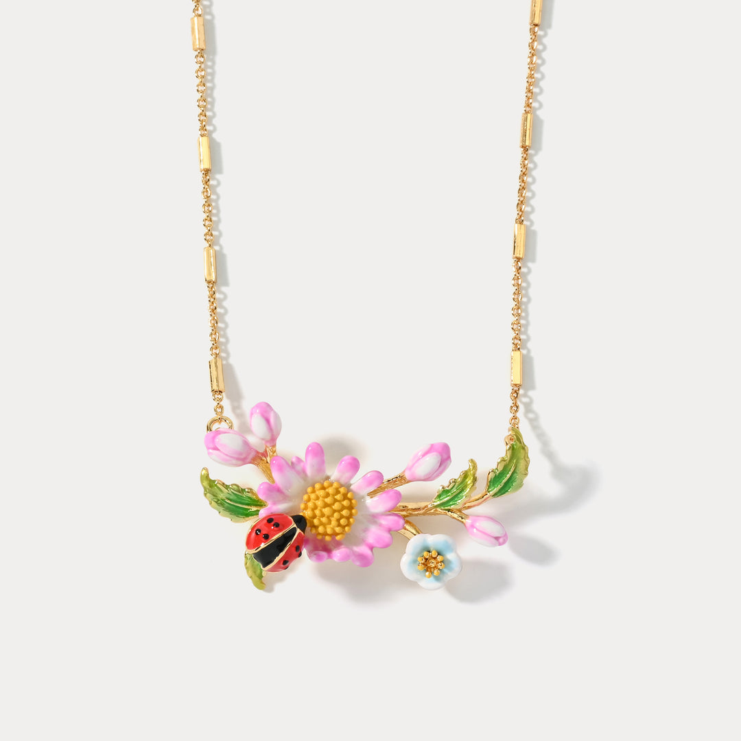 Zoomed-in image of the daisy flower and ladybug pendant on the necklace