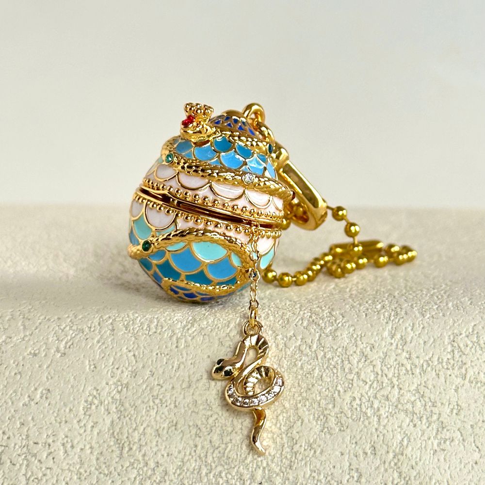 Detailed view of Snake Locket Pendant with coiled snake pattern, enamel scales, and hanging gold snake charm
