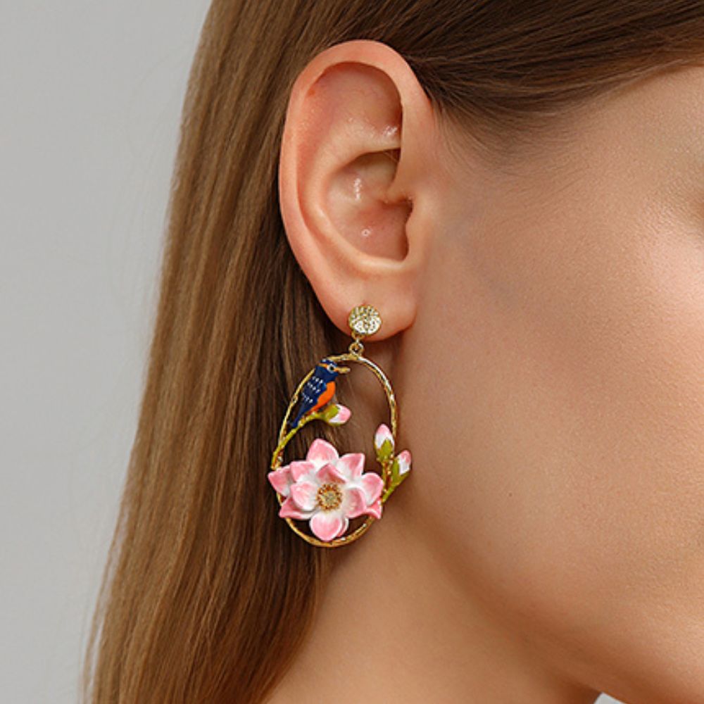 Side view of model wearing bird and lotus hoop earrings with vibrant detailing