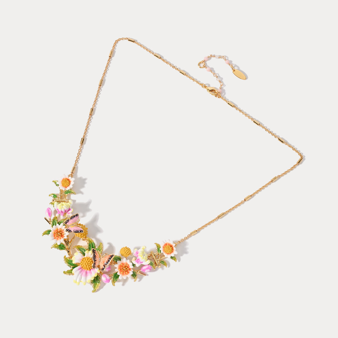 Gold chain necklace with pink daisy and ladybug pendant on white background