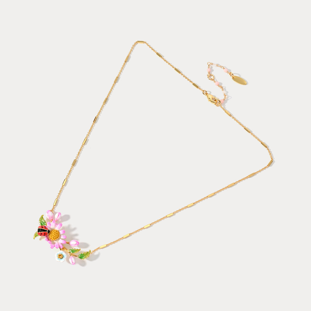 Gold chain necklace featuring a daisy and ladybug pendant displayed flat