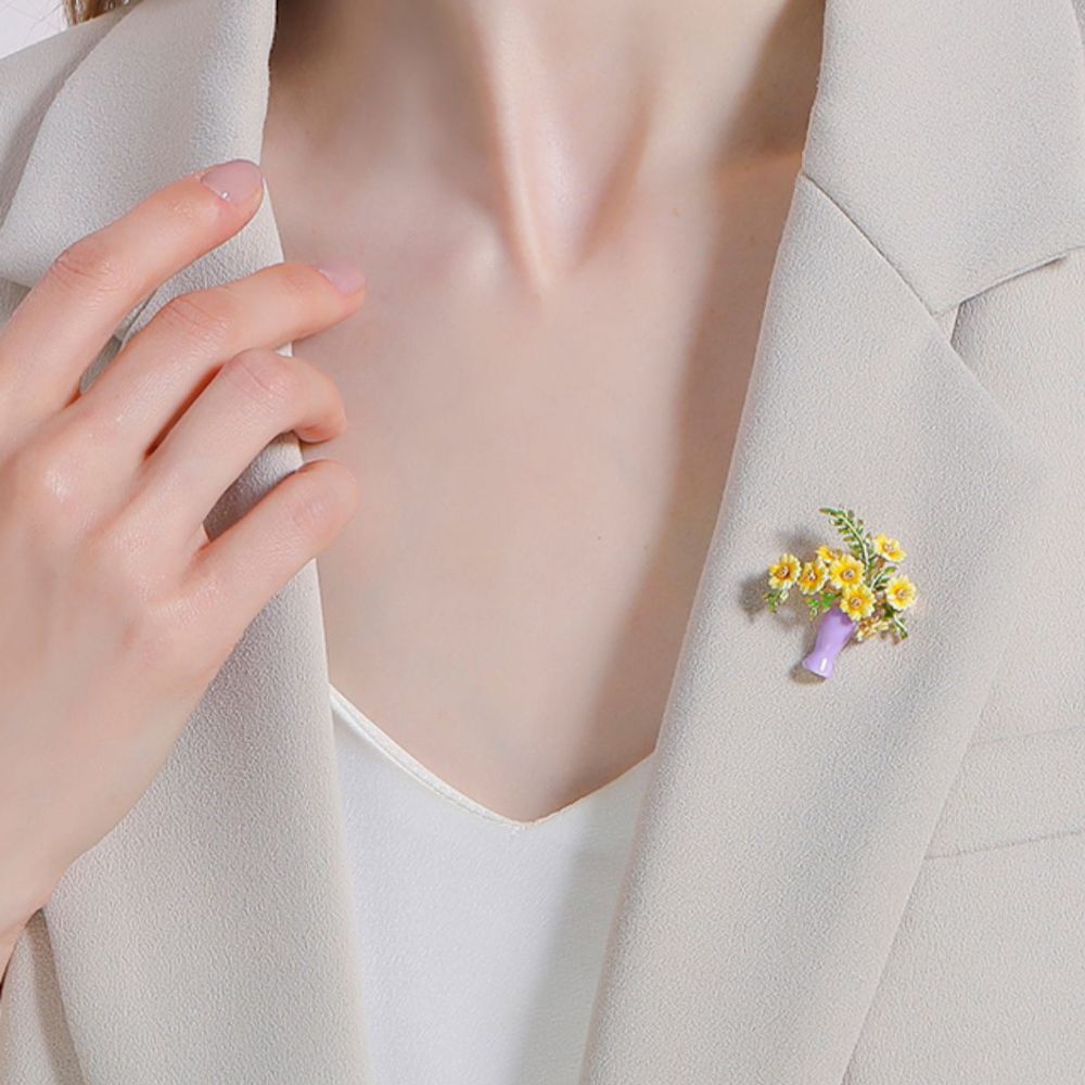 Full front-facing image of sunflower brooch with vibrant yellow petals and green leaves in a purple enamel vase