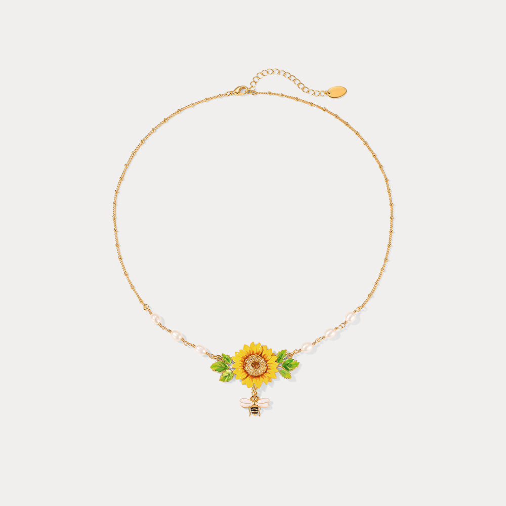 Flat display of gold-tone sunflower necklace with pearls and enamel bee detail