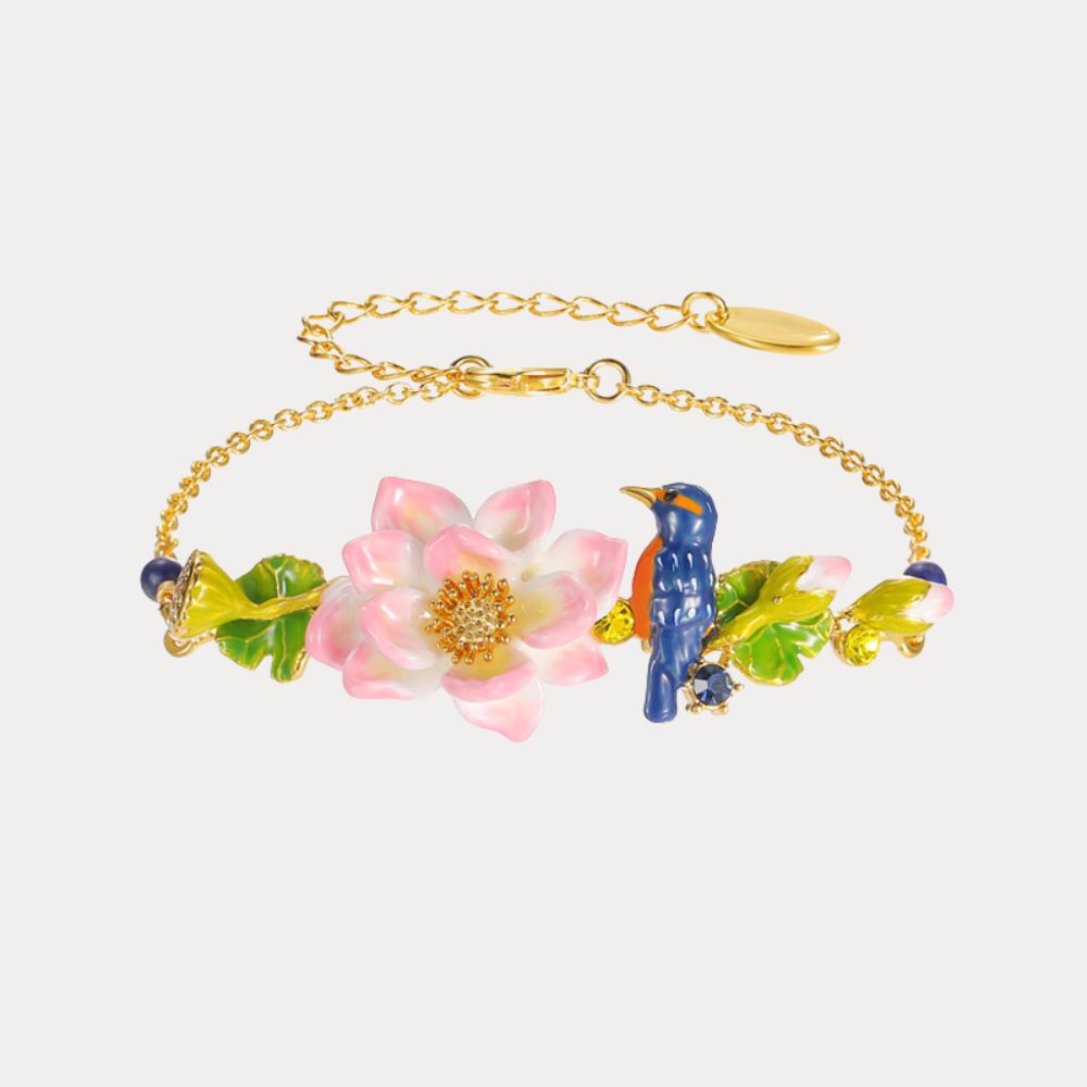 Gold-tone bracelet featuring a blue kingfisher bird, pink lotus flower, and enamel leaves, laid flat with visible clasp and extender chain.
