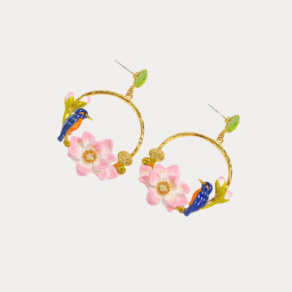 Pair of gold hoop earrings with pink lotus flowers and blue kingfisher birds perched among lotus seed pods, shown at an angle on a white background.