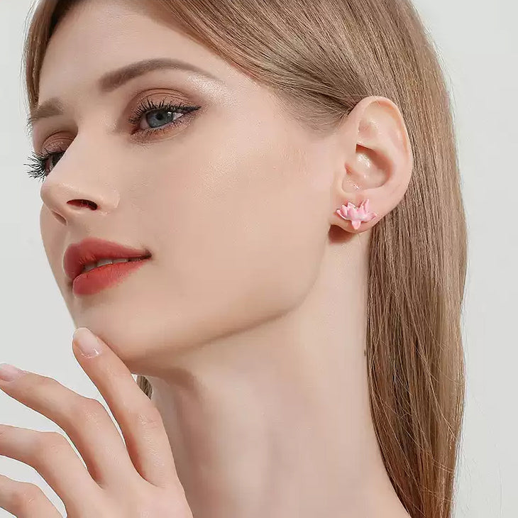 Model wearing lotus enamel earrings on both ears, showing the delicate flower design in a full-face view with light makeup.