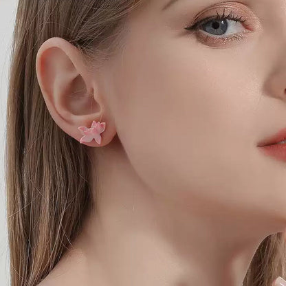 Close-up of a woman wearing a pink lotus enamel earring on her right ear, showcasing the small floral stud design.