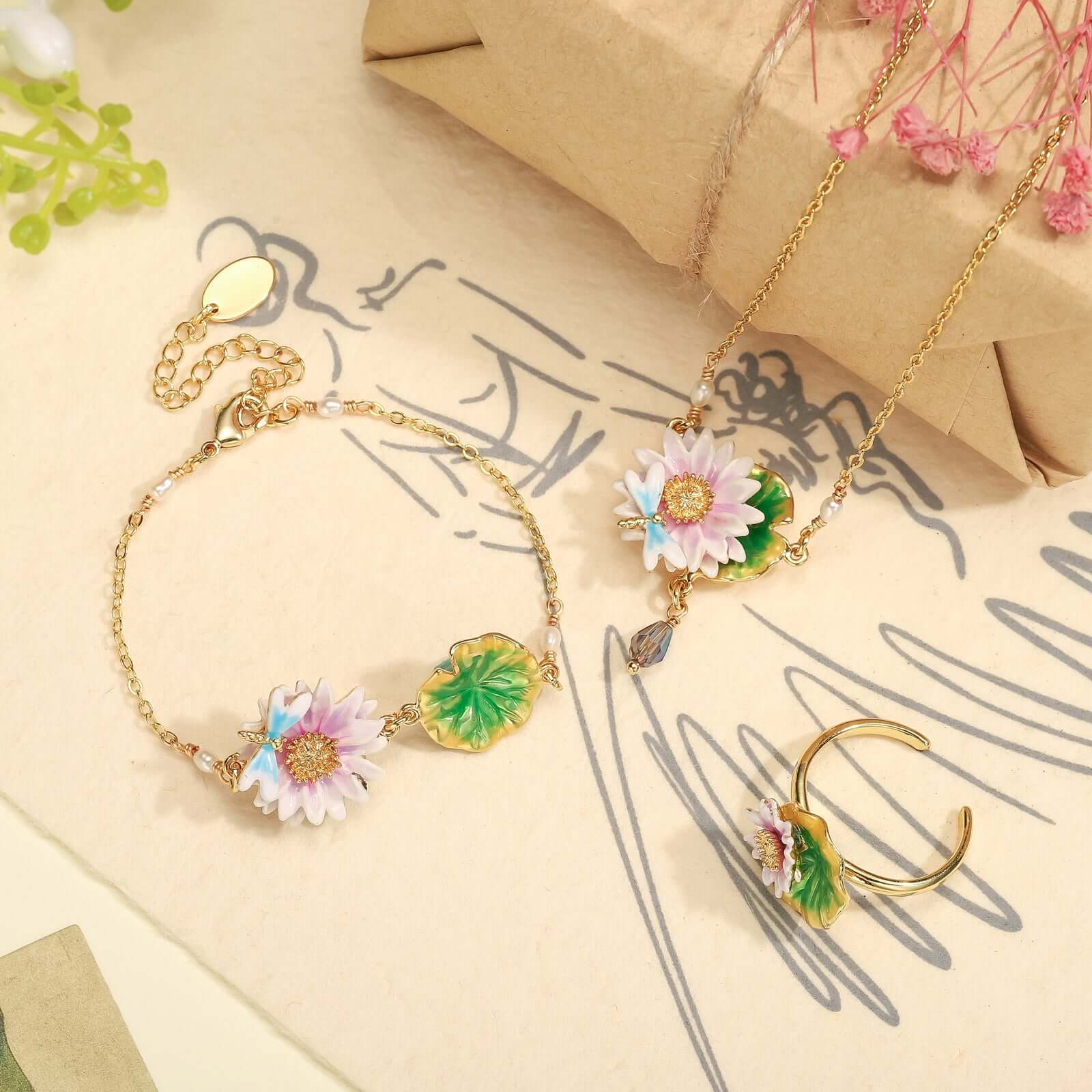 Full lotus jewelry set including enamel lotus ring, necklace, and bracelet laid on paper background
