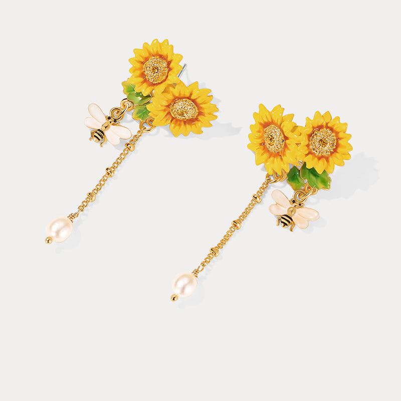 Detailed angled view of sunflower earrings with vibrant yellow petals, green leaves, and pearl tassels