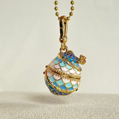 Close-up of Snake Locket Pendant shaped like a blue and white enamel egg with crown detailing and gold clasp