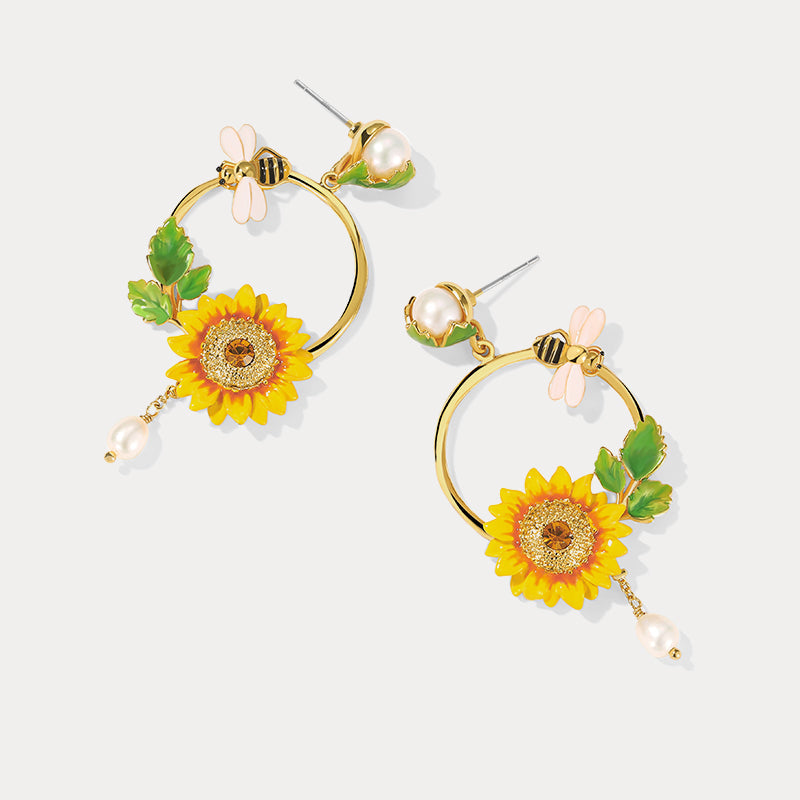 Pair of Sunflower Hoop Earrings with bee, pearl, and floral accents on flat background